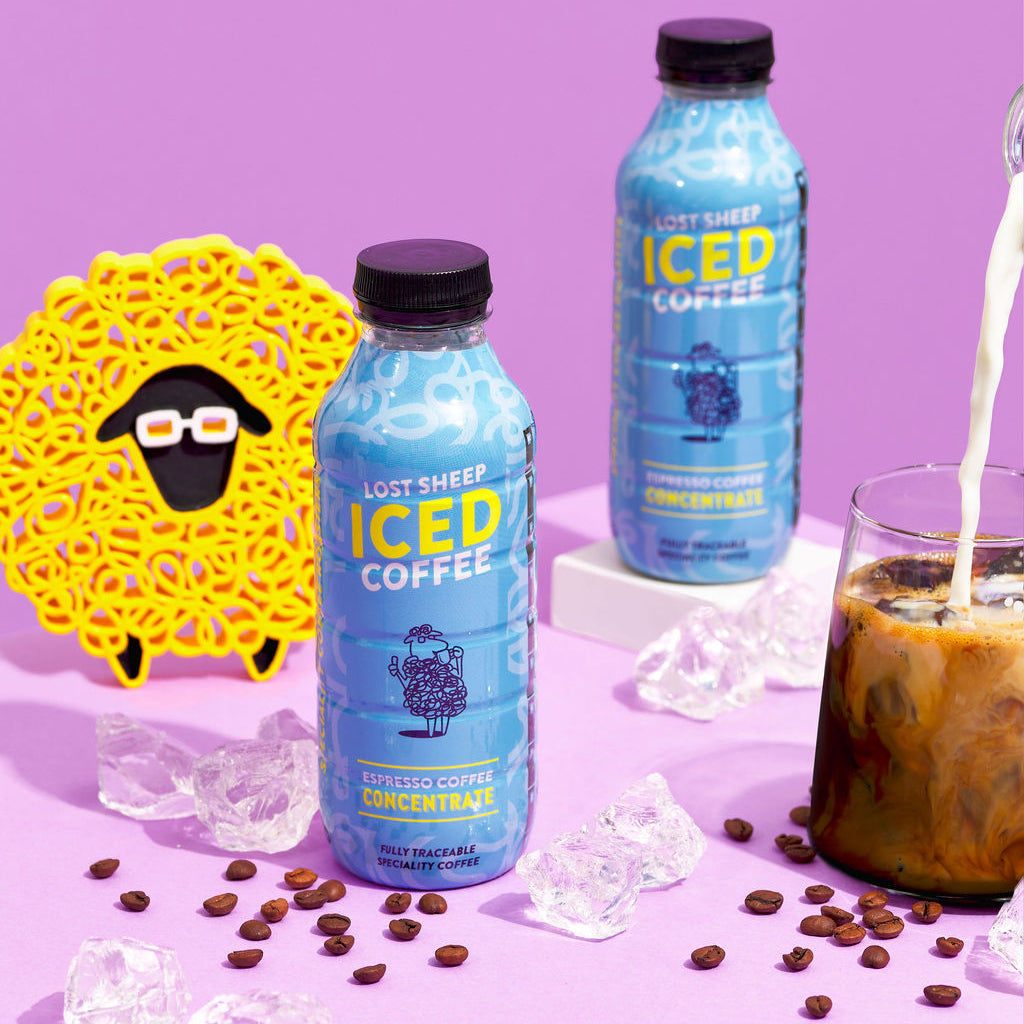 Lost Sheep ICED Coffee bottles with a glass of iced coffee and coffee beans on a purple background.