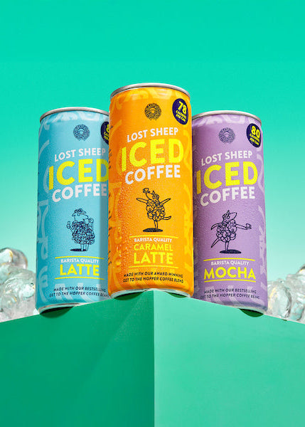 Three cans of Lost Sheep iced coffee on a green background